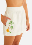 White shorts with palm tree and flower design worn by a person on a white background