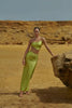 Model wearing the Grasshopper-colored Cala Set, featuring a one-shoulder top with wraparound tie and a midi-length skirt with side slit.