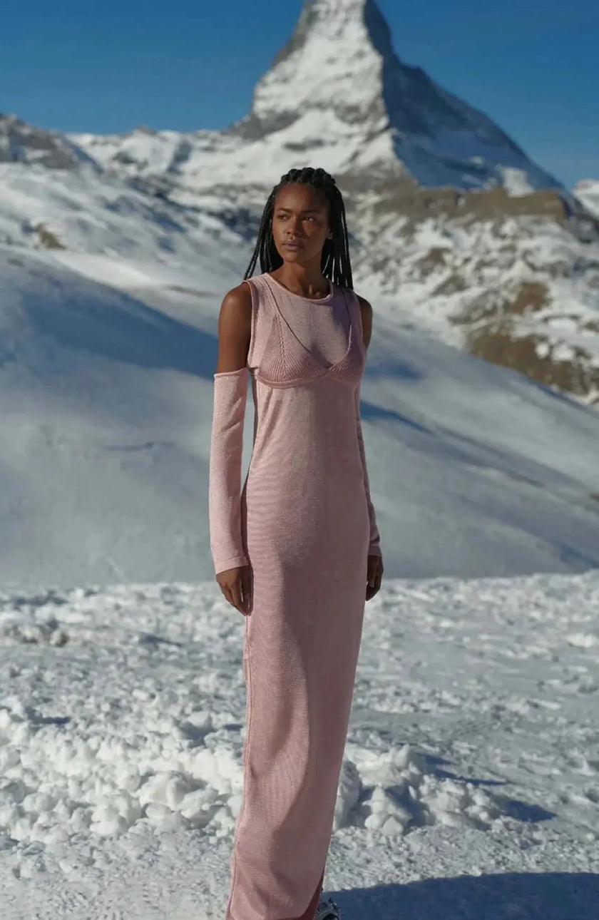 Model wearing the Della Dress in delicate pink, showcasing its round neckline and off-shoulder design with long sleeves.