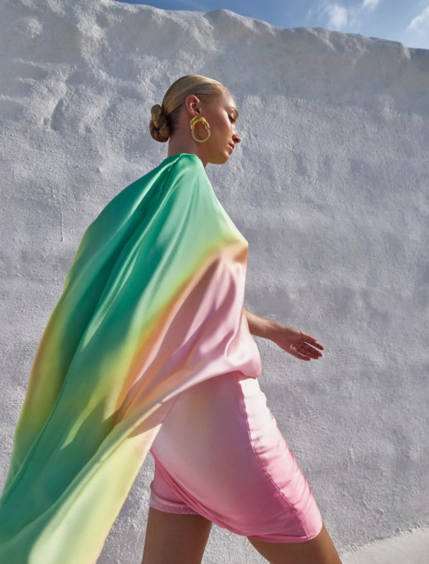 Model in the Dolly Dress walking under the sun, showcasing its ombré green, yellow, and pink tones in motion.