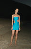 Model wearing the Azulado-colored Mambo Asymmetric Mini Dress, showcasing its strapless design with side cutouts and mini length.