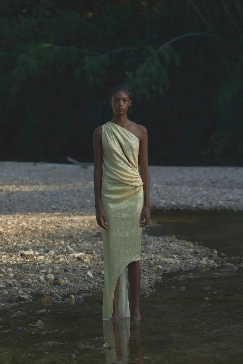 Side view of the Noe Dress in Sunshine, emphasizing the draped fabric and asymmetric hemline.