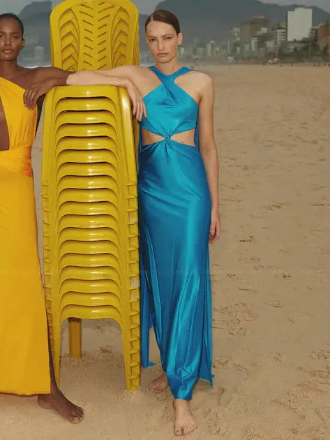 Model wearing the Ribera Maxi Dress in Amber, showcasing its halter neckline, side cutouts, and thigh-high slit.