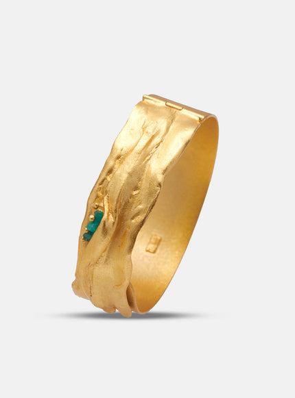 Close-up of the Bimy bracelet, handcrafted in 24k gold-plated bronze with textured surface and embedded Colombian emeralds.