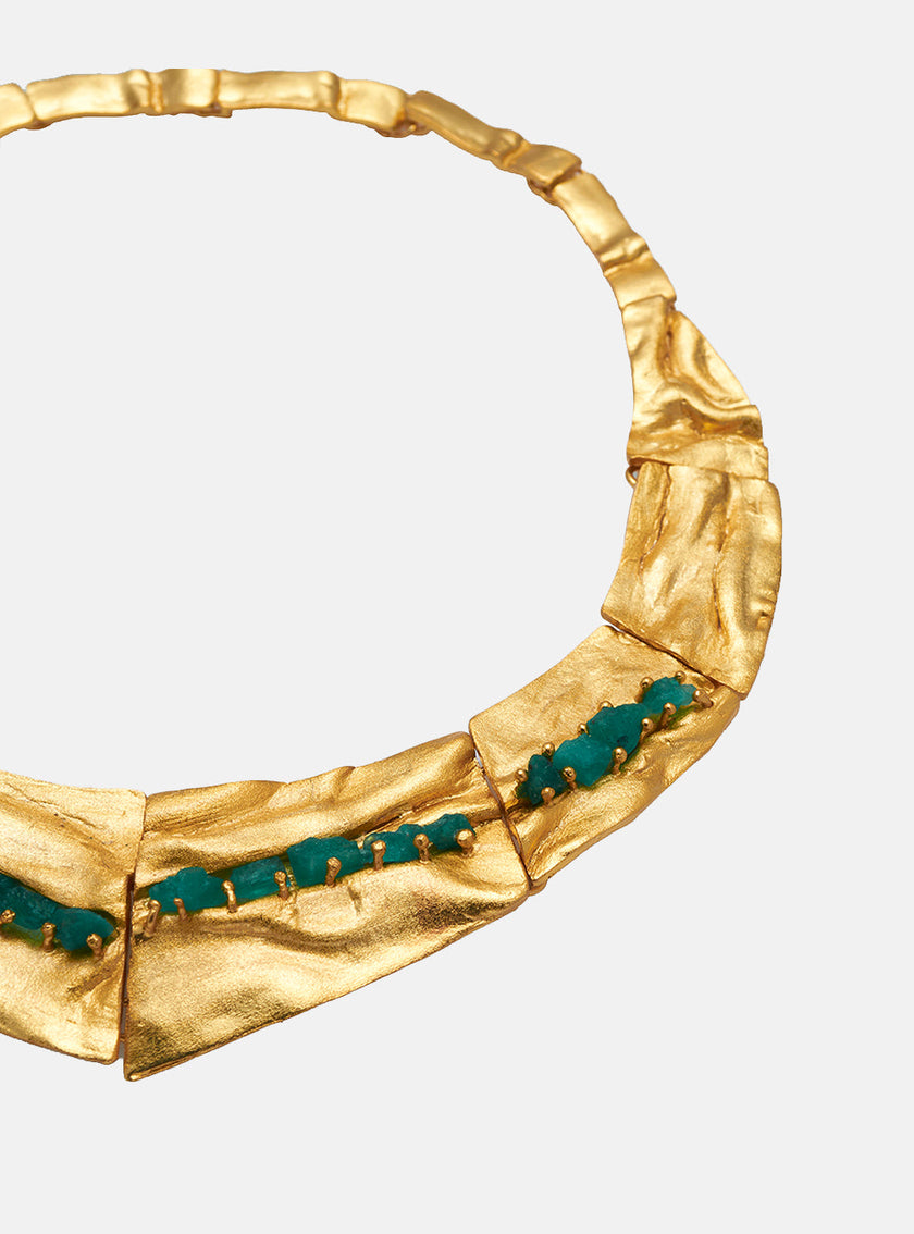 Close-up side view of the Bimy necklace, showing Colombian emeralds set into sculptural, gold-plated bronze surfaces.