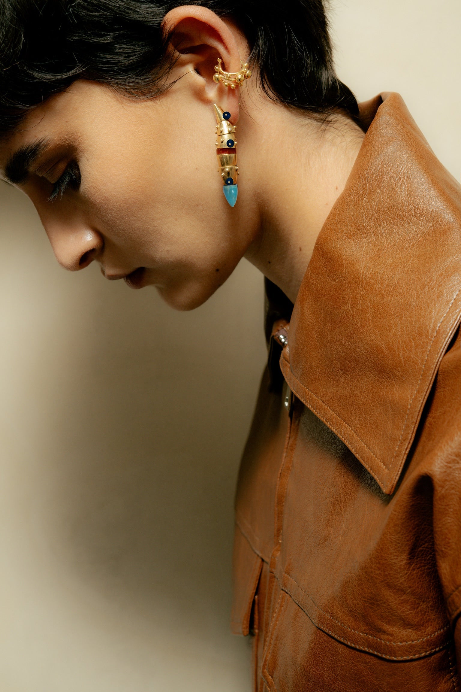 Person wearing a brown leather jacket with a neutral background