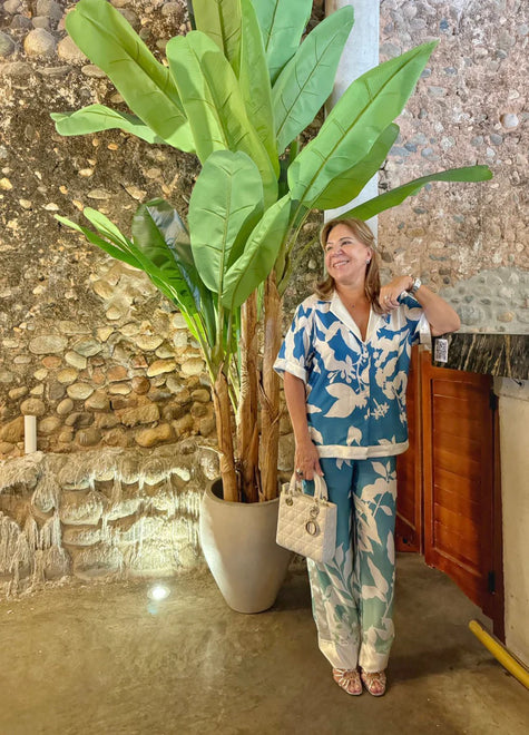 Model wearing the Eloisa Long Set by ANTIBES in Punta Cana, featuring a silky, tropical-print ensemble in shades of blue and green, styled with nude heels and a confident pose under moody lighting.