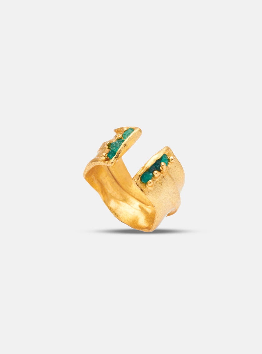 Close-up of a handcrafted open gold ring with embedded rough Colombian emeralds and a textured finish.