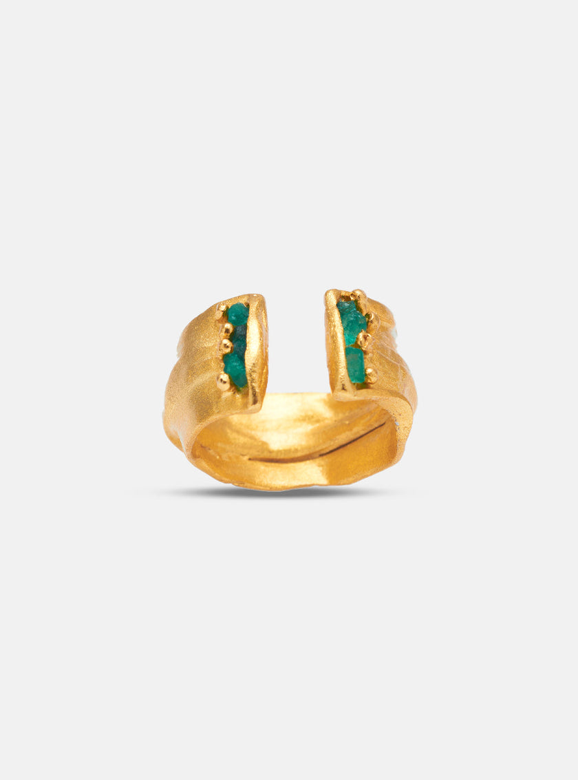 Detailed side view of the Hikysa ring featuring an asymmetrical gold band and vertical row of raw emeralds.