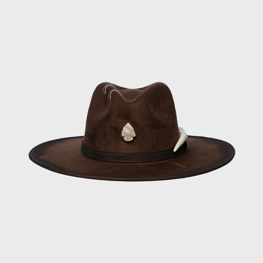 Brown wide-brimmed handmade felt hat with cream details and tribal charm, presented on a plain background.