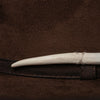 Close-up of cream hand-carved tooth detail wrapped in thread, attached to dark brown luxury felt hat.