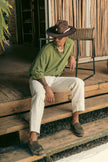 Model wearing Hunter hat by Mamba Hats while sitting on rustic wooden stairs, surrounded by Caribbean decor