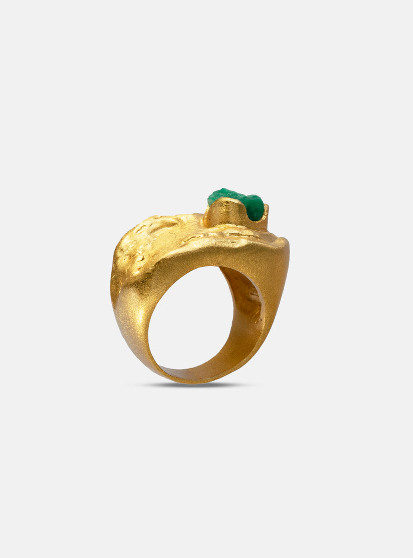 Close-up of Hyba ring in 24k gold-plated bronze with a rough Colombian emerald centerpiece, showcasing organic surface texture.