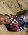 Person wearing a colorful checkered shirt lying on a sandy surface