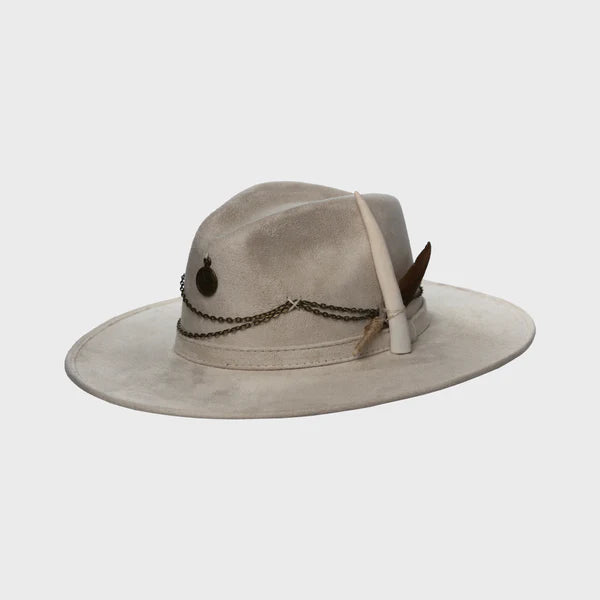Angled view of the Lucky Charm hat showing a bone-colored feather detail and rustic chains on warm beige vegan suede.