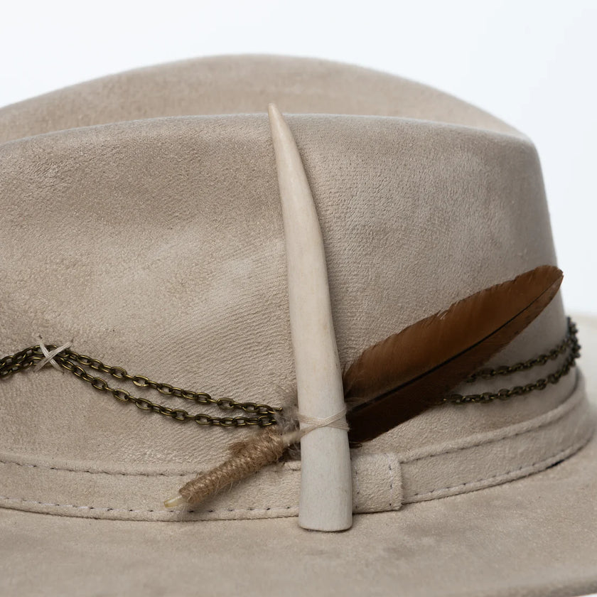 Macro shot of the feather and chain details on the Lucky Charm hat, highlighting craftsmanship and natural textures on brushed suede.
