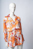 Back view of the model wearing the orange Lulo pajama set, highlighting the deep neckline and soft drape of the fabric.