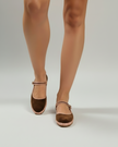 Brown sandals worn with beige tights on a white background