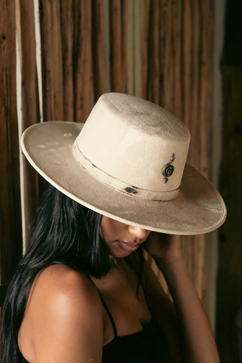 Top-angle view of the Mamba Charm hat slightly tilted over the model’s face, showcasing the soft velvety texture and sculptural metallic symbol.
