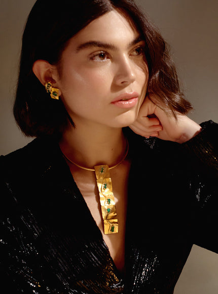 Portrait of a model wearing the Moky necklace and matching earrings, styled with a deep V-neck black dress.