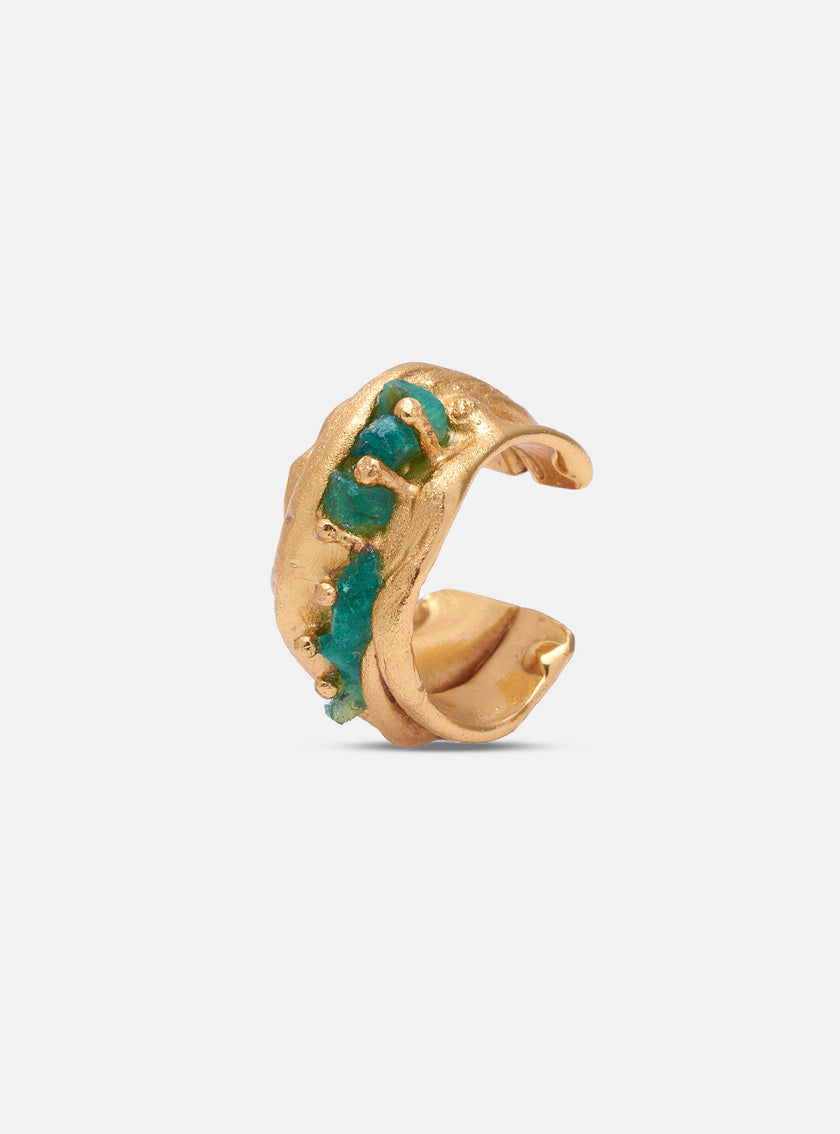 Gold earcuff featuring embedded rough-cut emeralds, with an organic, textured finish.