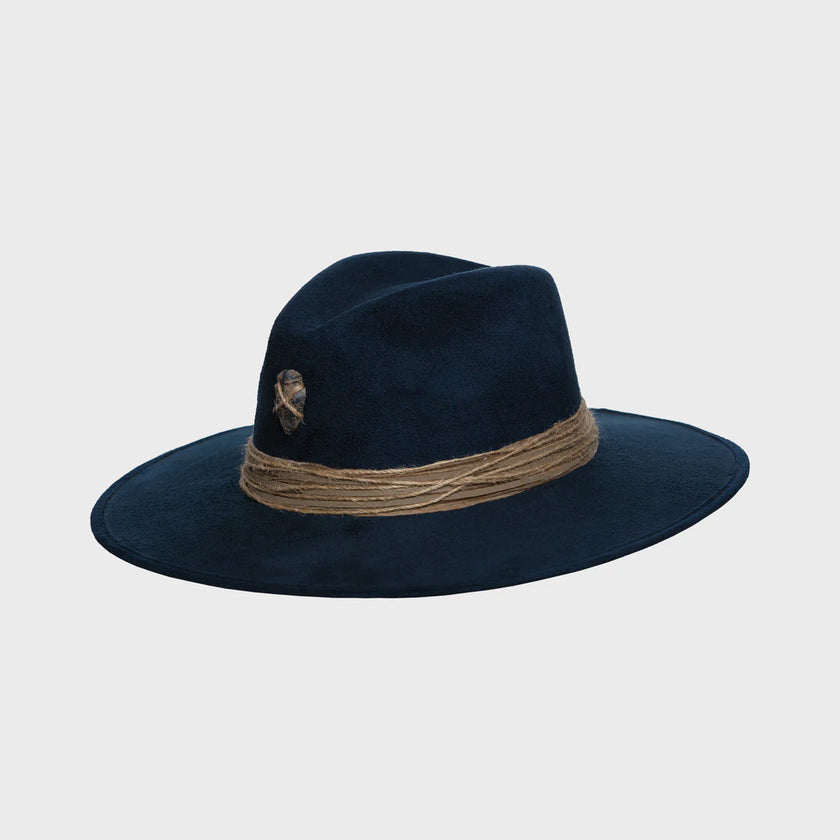 Angled side view of a handcrafted navy suede hat featuring rustic jute band and symbolic arrowhead detail.