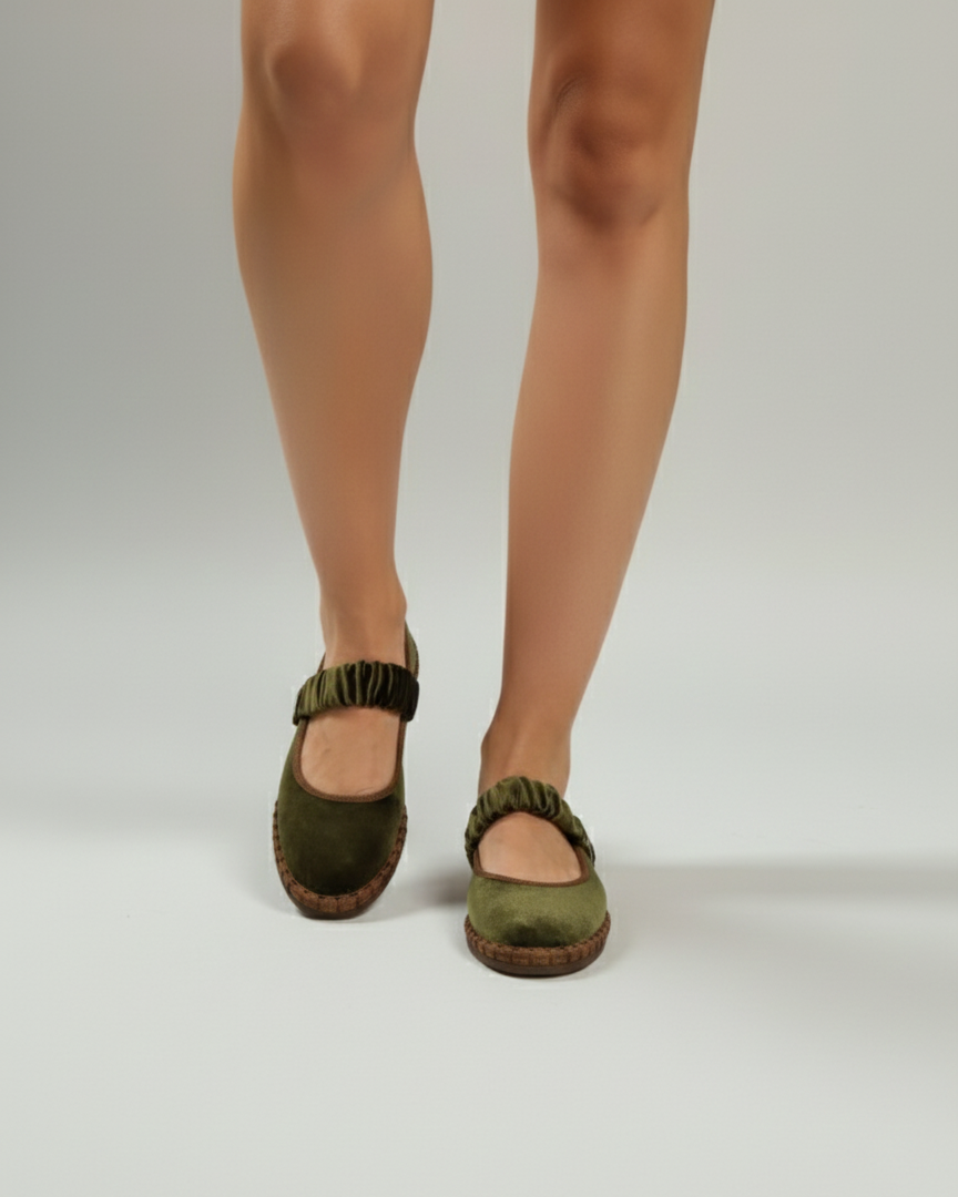 Green espadrille shoes worn by a person on a white background