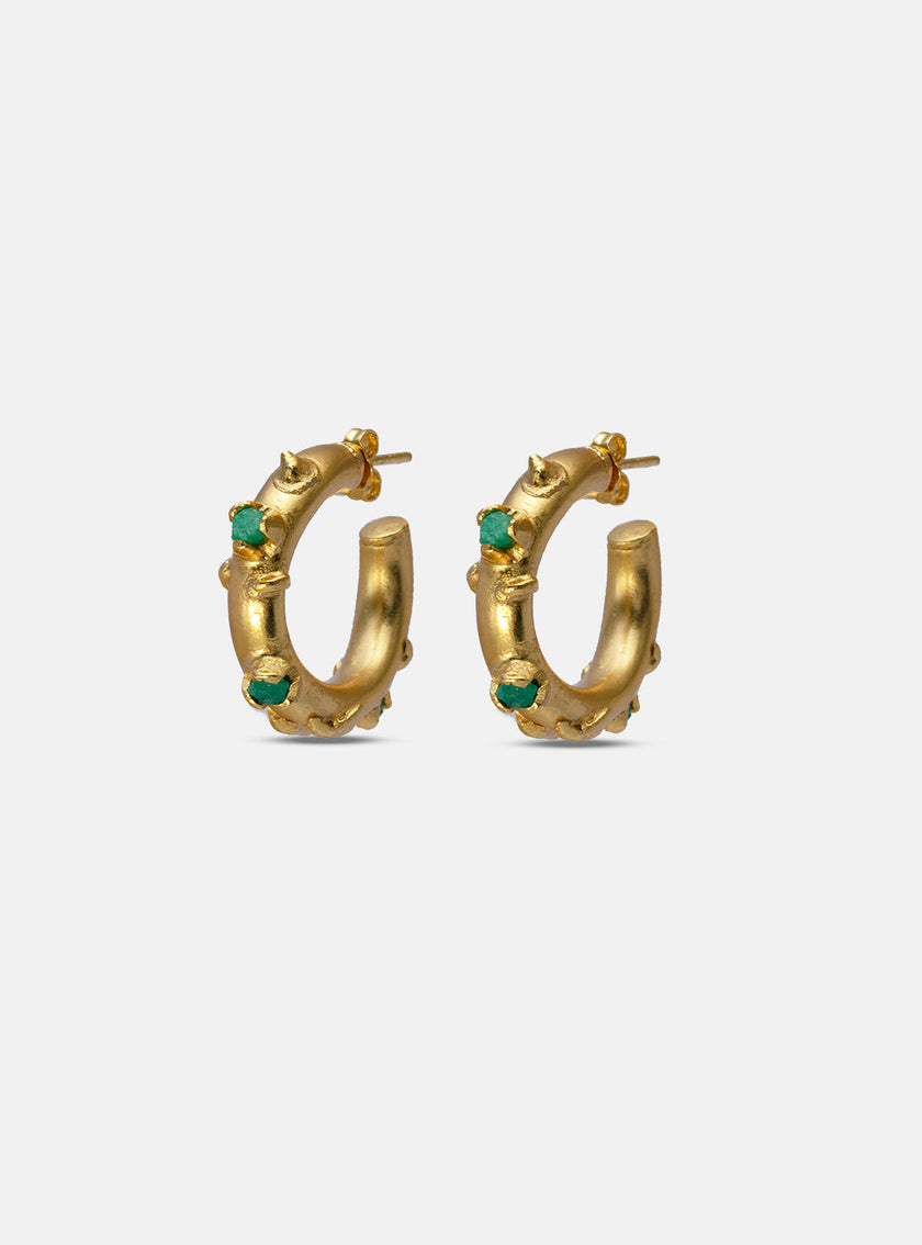 Close-up of handcrafted gold hoop earrings with embedded Colombian emeralds.