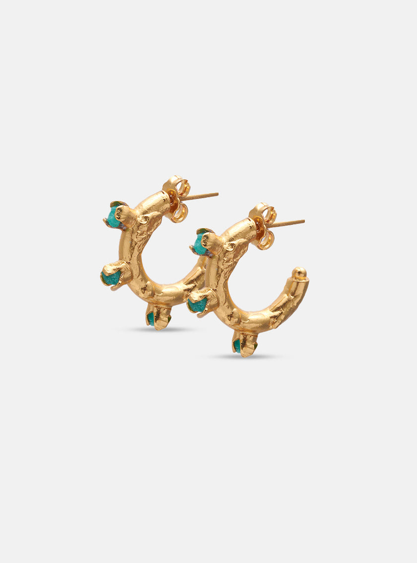 Close-up of handcrafted golden hoop earrings with embedded Colombian emeralds, displayed on white background.