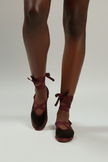 Brown high-heeled shoes with lace-up design worn by a person on a white background